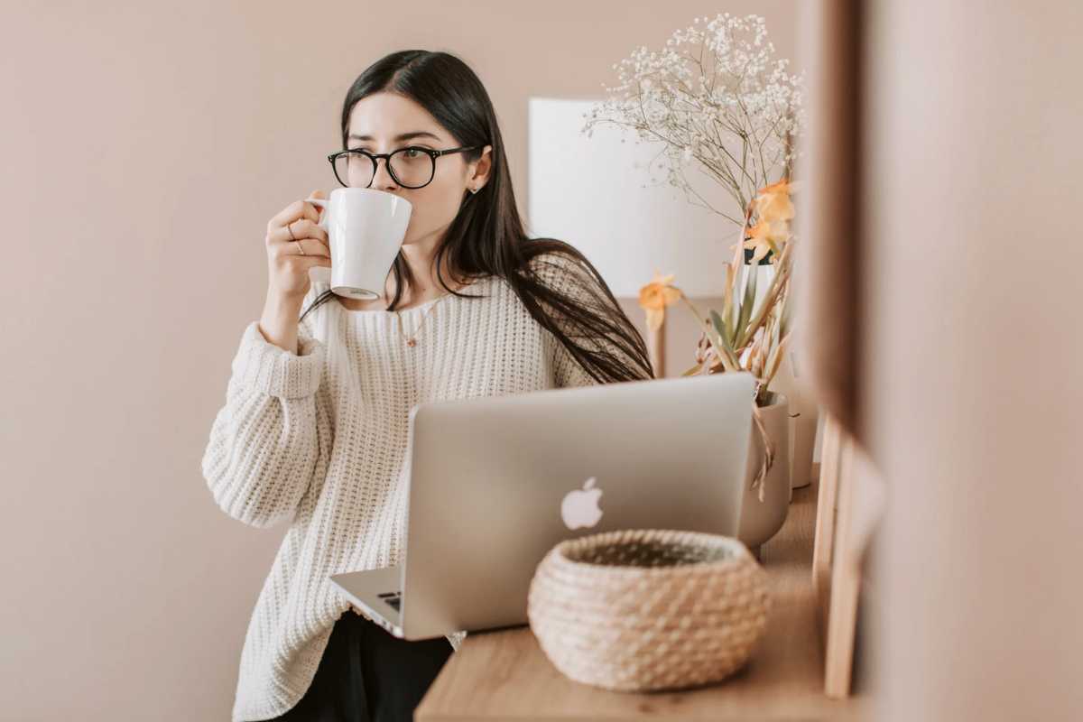 Donna con pc che beve da una tazza