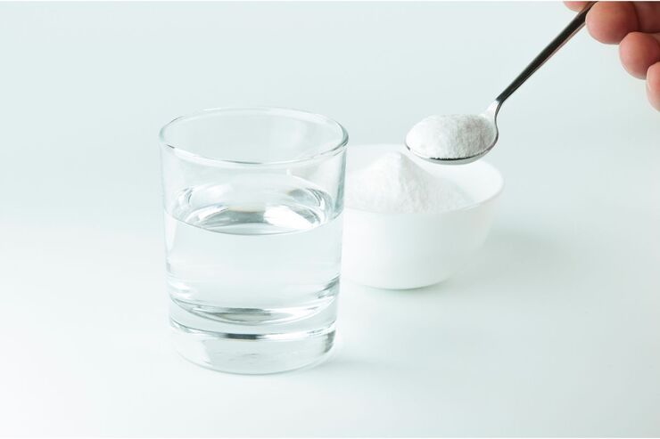 Cucchiaio con polvere bianca, bicchiere con acqua