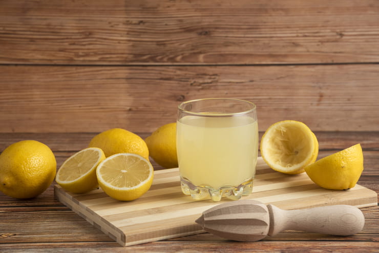 Bicchiere di succo di limone circondato da limoni