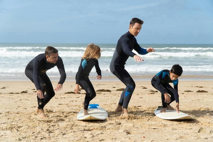 Istruttori e bambini su tavole da surf in spiaggia
