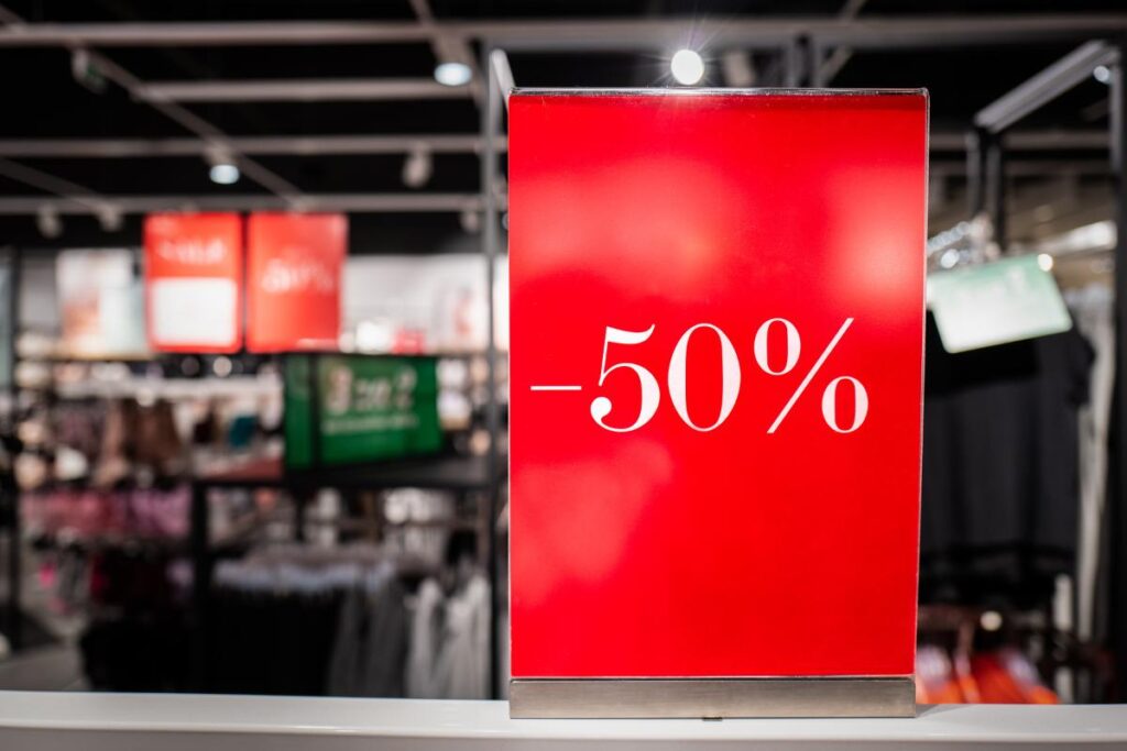 Cartello rosso saldi -50% dentro ad un negozio di abbigliamento
