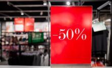 Cartello rosso saldi -50% dentro ad un negozio di abbigliamento