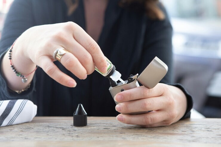 Ragazza che riempie con una ricarica la sigaretta elettronica