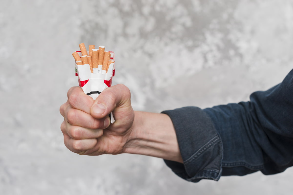 Uomo che stringe un pacchetto di sigarette schiacciandolo